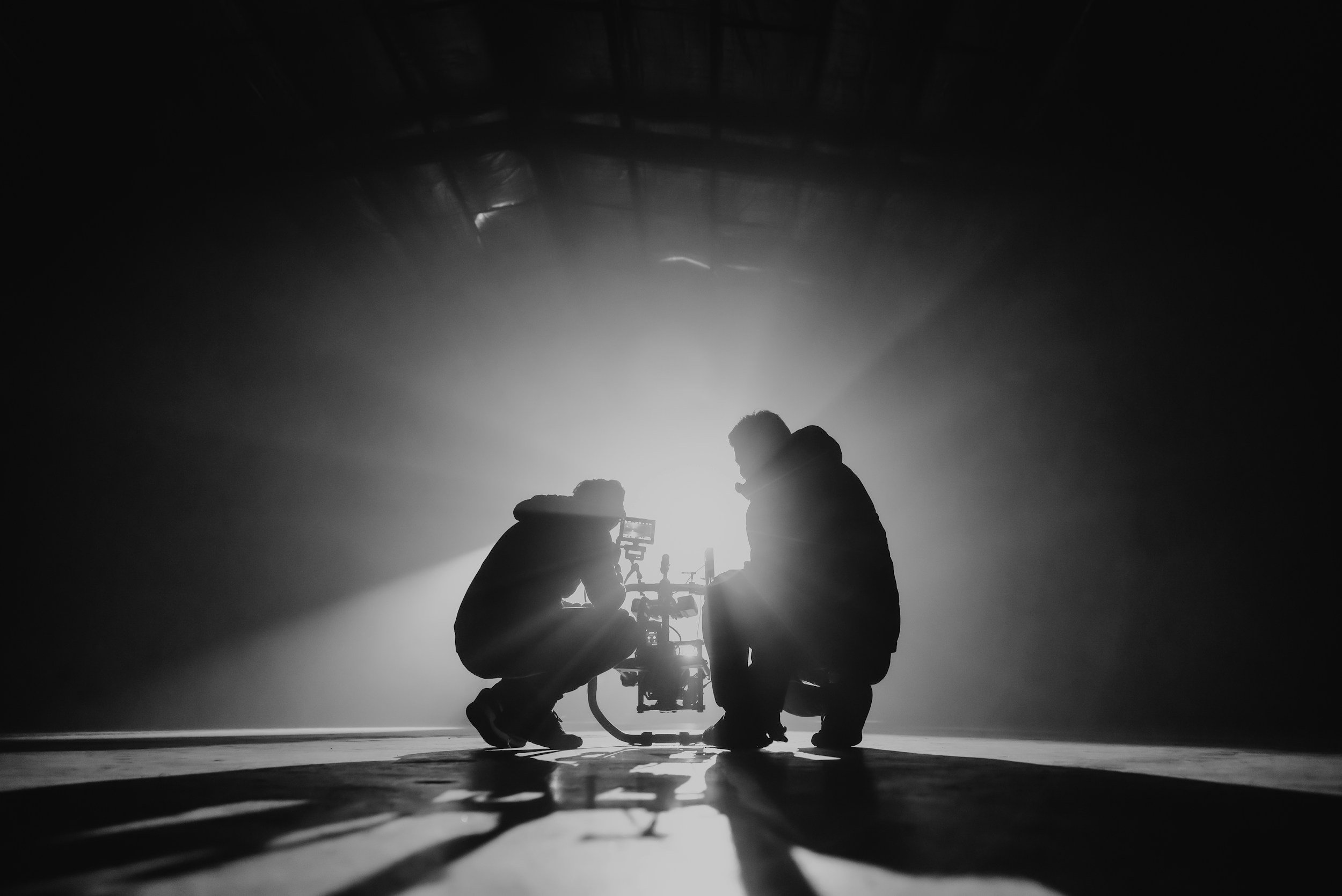 Two filmmakers silhouetted in dramatic light